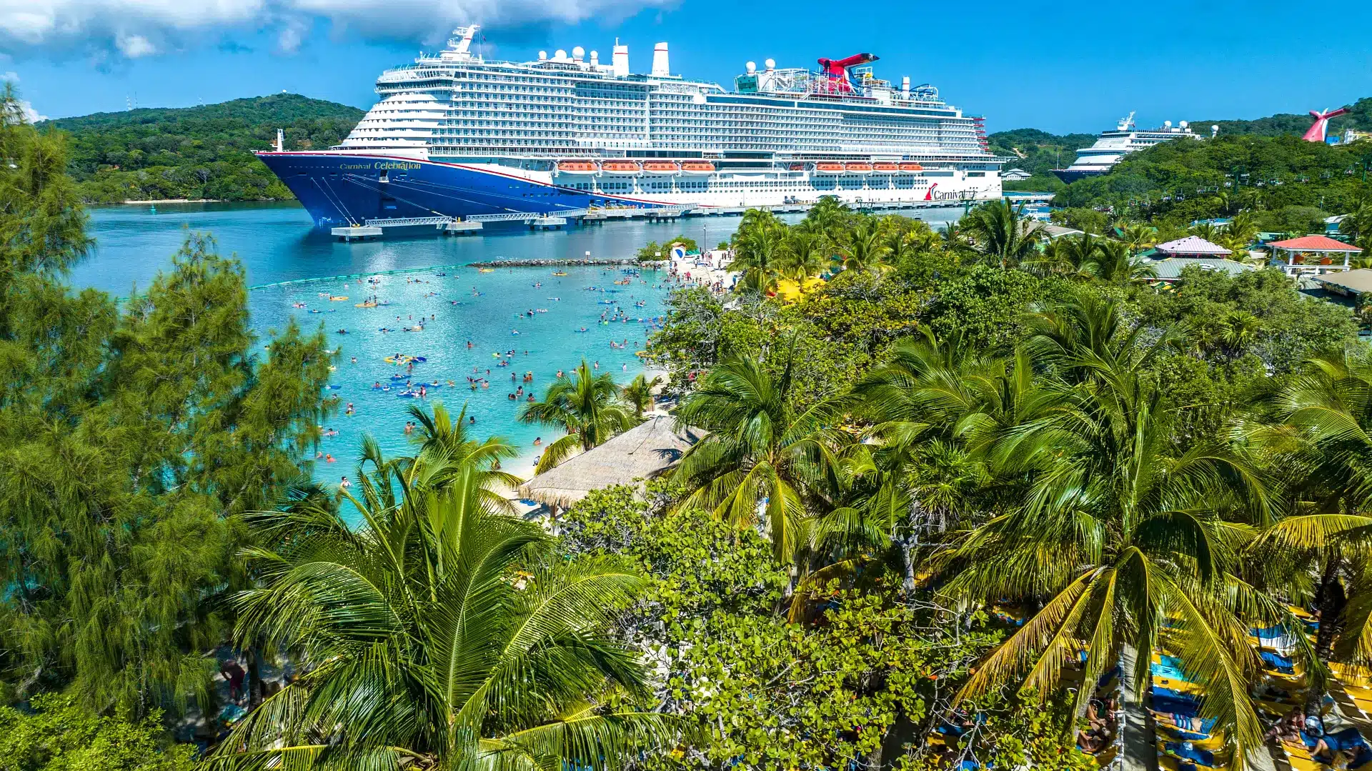 Cruiseschip in een tropische Caribbean-haven met palmbomen, turquoise zee en strand vol vakantiegangers