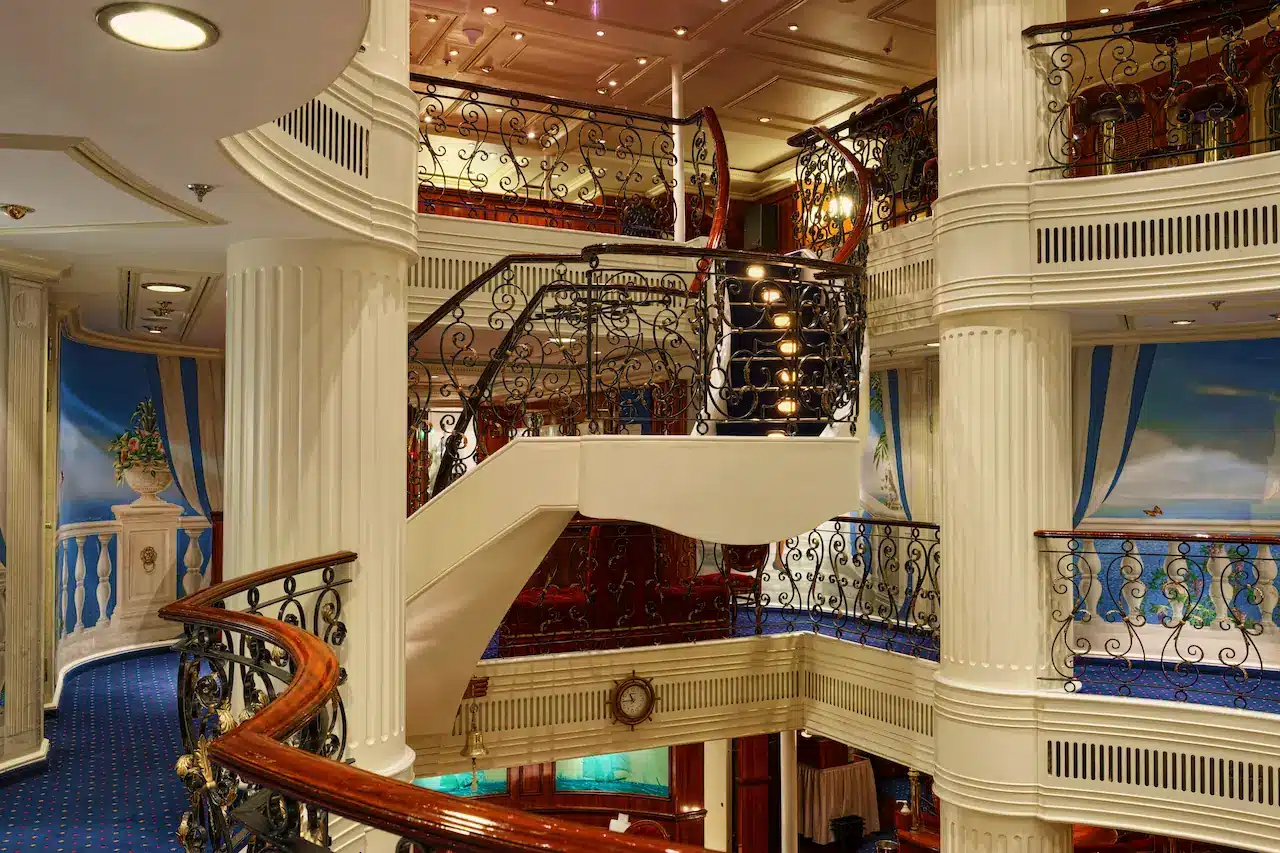 Het klassieke interieur van de Royal Clipper met een indrukwekkend drie verdiepingen hoog atrium, witte zuilen, sierlijke smeedijzeren trappen en maritieme muurschilderingen.
