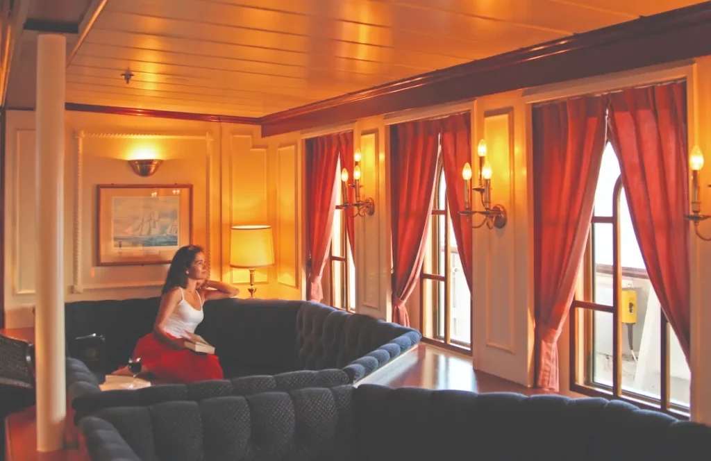 Het sfeervolle interieur van de lounge en Tropical Bar aan boord van de Star Clipper, met comfortabele blauwe banken, witte pilaren en een klassieke maritieme afwerking.