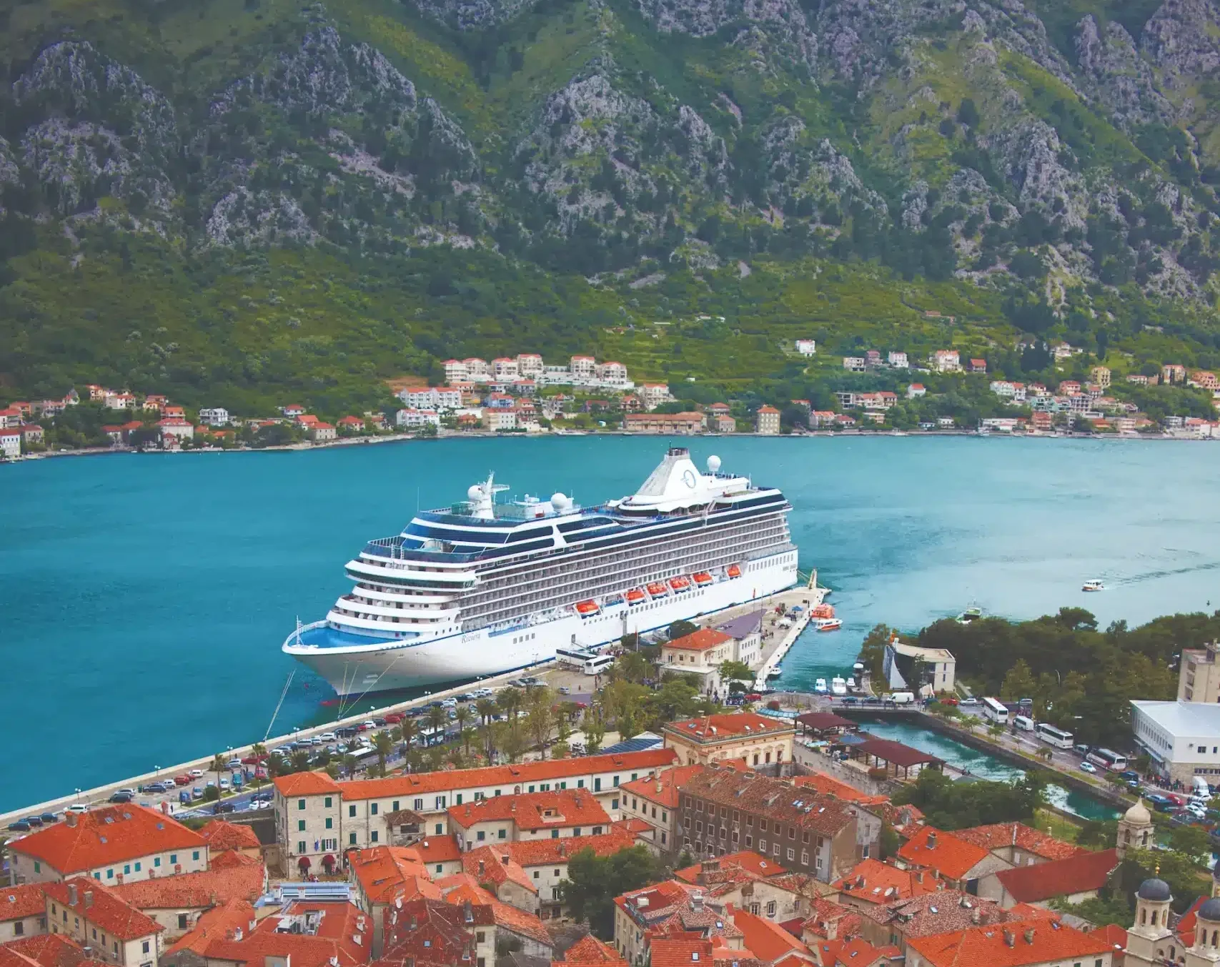 Cruiseschip aangemeerd in de baai van Kotor met uitzicht op de oude stad en bergen in Montenegro