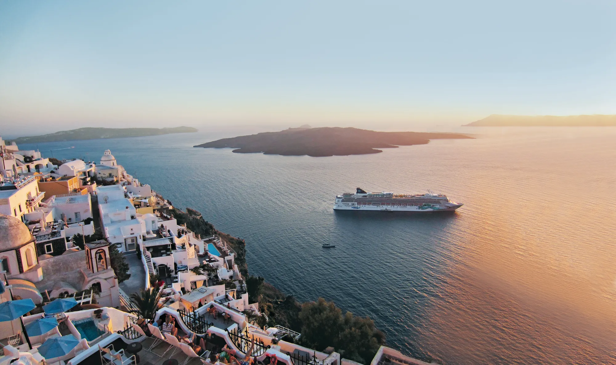 Cruisenschip NCL Jade voor de kust van Santorini in Griekenland bij zonsondergang
