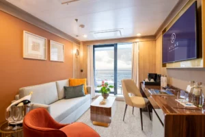 De zithoek van een Discovery Suite op een Atlas Ocean Voyages schip met uitzicht op de oceaan.