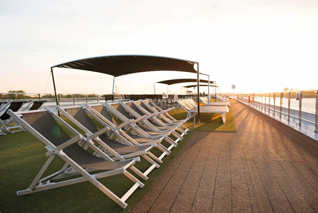 Zijaanzicht van het Sun Deck van de Emerald Liberté met rijen moderne ligstoelen en zonneschermen tijdens een zonnige middag op de rivier.