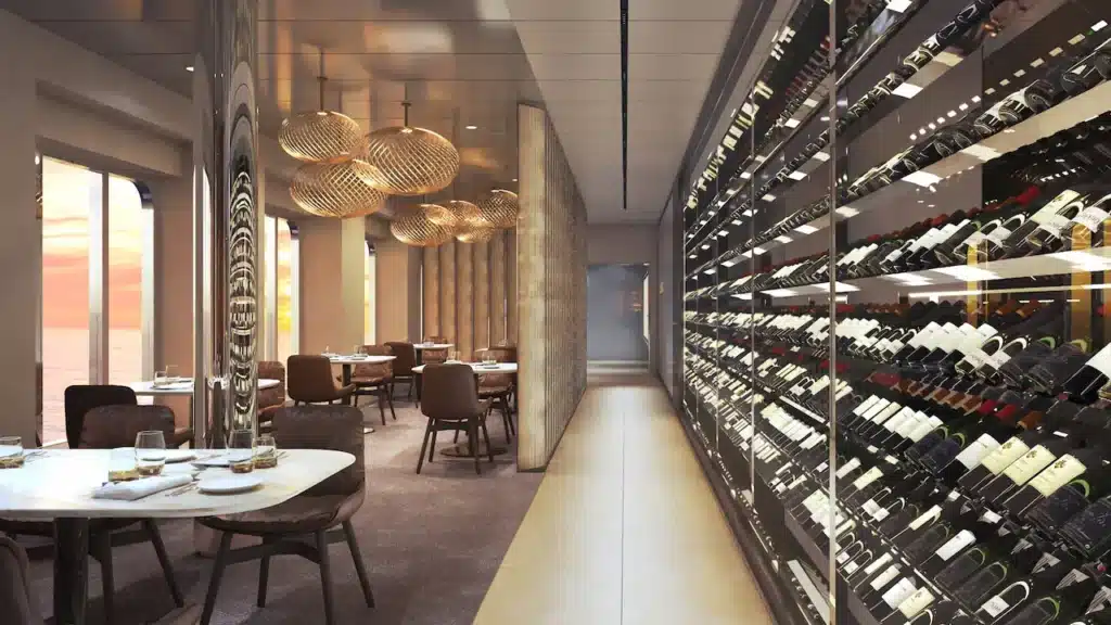 Interieur van het Elements restaurant aan boord van de Scenic Ikon met een indrukwekkende glazen wijnkast en uitzicht op zee bij zonsondergang.